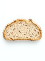 Sliced artisan bread with golden crust and airy crumb structure, isolated on white background for bakery, food packaging, and culinary design projects.