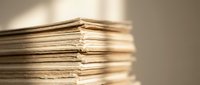 Stack of aged vintage paper documents with rough edges creating warm nostalgic atmosphere for historical research and archival projects.