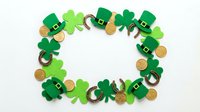 St. Patrick's Day festive frame with green shamrocks, leprechaun hats, horseshoes and gold coins on white background for holiday greeting cards and decorations.