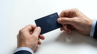 Two hands exchanging a dark blue card with trust symbol against white background, isolated for business and financial design use.