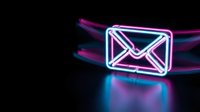 Glowing neon email envelope icon with vibrant pink and blue light trails on dark background for digital communication and marketing concepts.