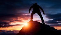 Silhouette of determined climber reaching mountain summit at dramatic sunset with vibrant orange sky and dark stormy clouds. Achievement concept.