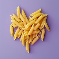 Raw penne pasta arranged in heart shape on purple background. Minimalist food photography with clean composition and soft lighting for creative culinary design.