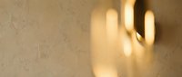Hand shadow silhouette cast on textured beige wall with warm golden sunlight creating dramatic lighting effect for interior design concepts.