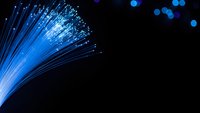 Blue fiber optic cables with glowing light transmission on black background for technology and telecommunications concepts.