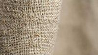 Natural beige burlap fabric texture with woven fibers in soft focus, organic textile material for rustic home decor and craft projects.