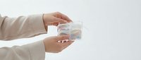 Professional hands holding transparent glass bowl with colorful pills and capsules for healthcare and medical treatment concepts.