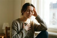 Young woman experiencing chest pain and headache sitting by window in cozy sweater, health anxiety and stress symptoms concept for medical awareness.