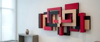 Modern geometric wall art installation with interlocking rectangular frames in red, black, and wood tones creating contemporary sculptural decor.
