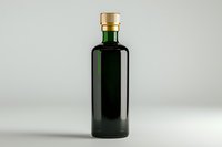 Dark green glass bottle with golden cap on light gray background, minimalist product photography for beverage, oil or cosmetic packaging design.