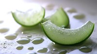 Fresh cucumber slices with water drops on light surface, macro shot showing juicy texture and natural moisture for healthy eating and spa concepts.