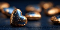 Golden heart-shaped decorations with glittering texture on dark blue background, creating romantic luxury atmosphere for Valentine's Day celebrations.