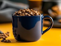 Dark blue ceramic mug filled with cinnamon granola cereal on bright yellow surface with scattered ingredients and blurred background for food styling.