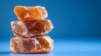 Stacked pink Himalayan salt crystals on blue background with soft lighting, showcasing natural mineral formation and crystalline texture for wellness concept.