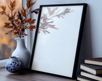 Mockup with black frame and autumn leaves in white ceramic vase on wooden table near window. Shadow play creates artistic composition for design presentation.