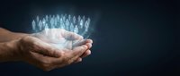 Male hands cupping glowing holographic human figures representing community support, teamwork and social connection for business presentations.