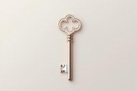 Vintage silver ornate key with decorative quatrefoil bow design isolated on beige background, suitable for jewelry design and antique collections.