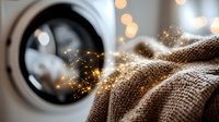 Fresh laundry with magical sparkles emerging from washing machine drum, soft beige textile with glowing particles against blurred bokeh background creates cozy atmosphere.