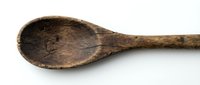 Aged wooden spoon with worn surface and natural patina, isolated on white background for culinary and rustic design projects.