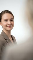 Young professional businesswoman smiling confidently in beige blazer with soft natural lighting and neutral background for corporate presentations.