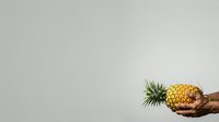 Ripe pineapple with green crown held in hand against neutral background, isolated for design use on merchandise and promotional materials.