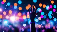 Silhouette of raised hand against vibrant bokeh lights in blue, orange and pink colors creating magical atmosphere at concert or party celebration.