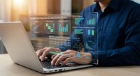 Professional businessman analyzing financial data and trading charts on laptop with holographic interface displays for investment and market research.