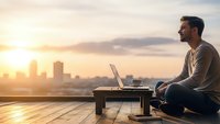 Young professional man working remotely on laptop at sunset rooftop terrace overlooking city skyline, digital nomad lifestyle and work-life balance concept.