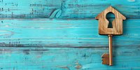 Wooden house-shaped key on turquoise rustic background with copy space. Real estate, home security and property concept for business presentations.