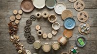 Assorted eco-friendly tableware and kitchenware made from sustainable materials arranged on rustic wooden background for zero waste lifestyle.