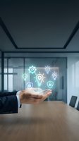 Businessman hand presenting glowing innovation icons with lightbulbs, gears and security symbols floating above palm in modern conference room for business concepts.