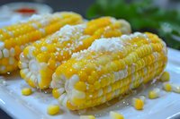 Fresh corn on the cob with melted butter and sea salt on white plate, healthy summer vegetable side dish for barbecue and outdoor dining occasions.