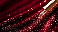 Luxurious cosmetic dropper with glowing red sparkles and bokeh effect against dark background, beauty product photography for skincare and serum advertising.