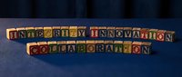 Colorful wooden alphabet blocks spelling integrity, innovation, and collaboration on a blue surface, representing core business values and teamwork concepts.