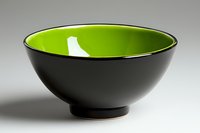 Modern ceramic bowl with matte black exterior and vibrant lime green interior on neutral background, showcasing minimalist Asian-inspired design for food styling.
