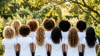 Diverse group of women with different hair textures and ethnicities wearing white shirts standing together outdoors in golden sunlight for unity concept.