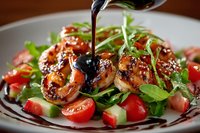 Grilled shrimp salad with fresh vegetables and balsamic glaze being poured over seafood dish, served on white plate for restaurant menu presentation.