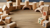 Wooden educational toy blocks with letters and numbers arranged in circle on natural wood surface for early childhood learning and development.