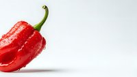 Fresh red bell pepper with water droplets isolated on white background for healthy cooking and nutrition concepts.