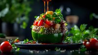 Stuffed green bell pepper with quinoa, cherry tomatoes and fresh herbs on dark background, drizzled with sauce. Food photography for healthy recipes.