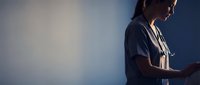 Young female healthcare professional in scrubs using tablet device in modern medical environment with dramatic lighting for digital health technology concepts.