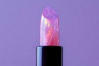 Clear jelly lipstick with pink flower inside against purple background, macro cosmetic photography showing transparent texture and floral detail.
