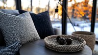 Cozy winter home interior with textured throw pillows and woven basket on sofa against snowy window view, creating warm hygge atmosphere for seasonal decor.