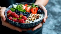 Fresh berries and granola in yogurt bowl with raspberries, blackberries, strawberries and crunchy toppings served for healthy breakfast on dark background.