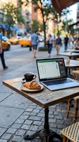 Laptop with spreadsheet open on outdoor cafe table beside coffee cup and croissant, urban street scene with pedestrians and yellow taxis blurred in background, remote work and freelance lifestyle.