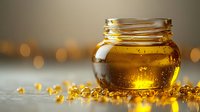 Golden honey in glass jar with scattered amber drops on reflective surface against blurred warm bokeh background, natural sweetener and healthy food concept.