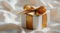 Elegant white gift box with luxurious golden ribbon and bow on soft silk fabric background for special occasions and celebrations.