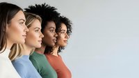 Four diverse women in colorful tops standing in profile showing unity and teamwork in modern workplace or community setting.