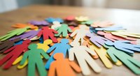 Colorful paper cutout figures in various shapes scattered on wooden surface representing diversity, teamwork and community concepts for creative projects.