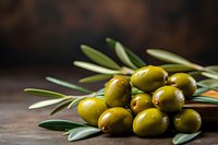 Fresh green olives and olive tree branch on rustic wooden background with copy space, natural light and selective focus for food photography.